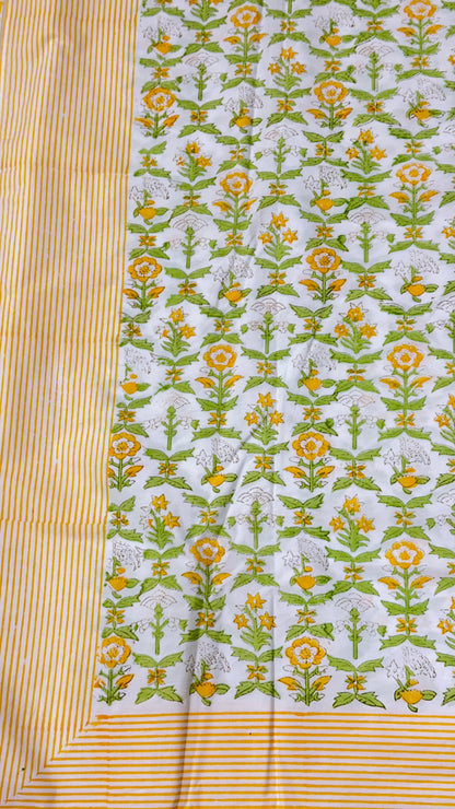 A close-up of a printed fabric panel with a white base, repeating yellow and green floral motifs, and a striped yellow border.